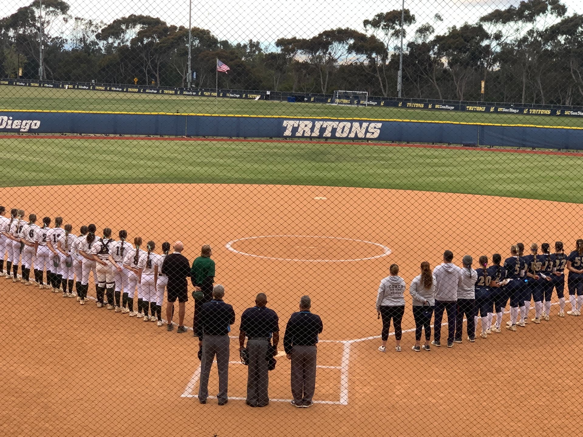 MOA umpires standing with both teams along the baselines before a game